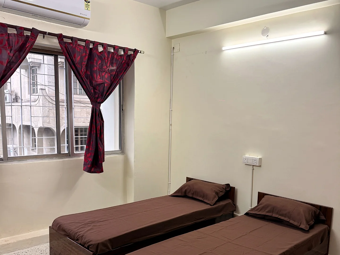 Bright twin-sharing room at Snehmili Girls PG with a window and air conditioning